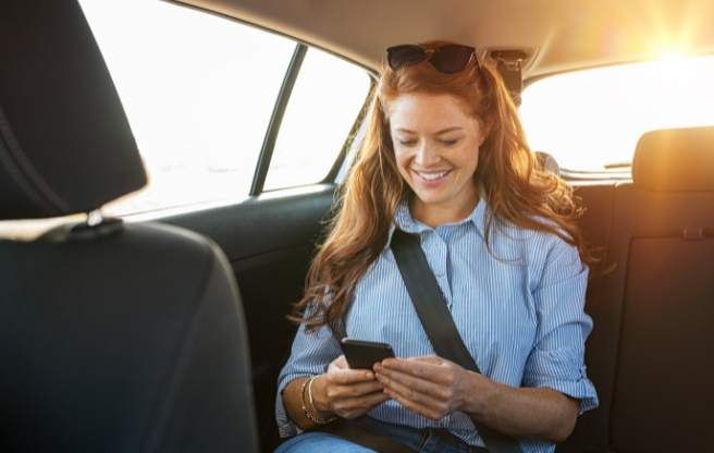 A passenger checking her phone while riding in a black car limo
