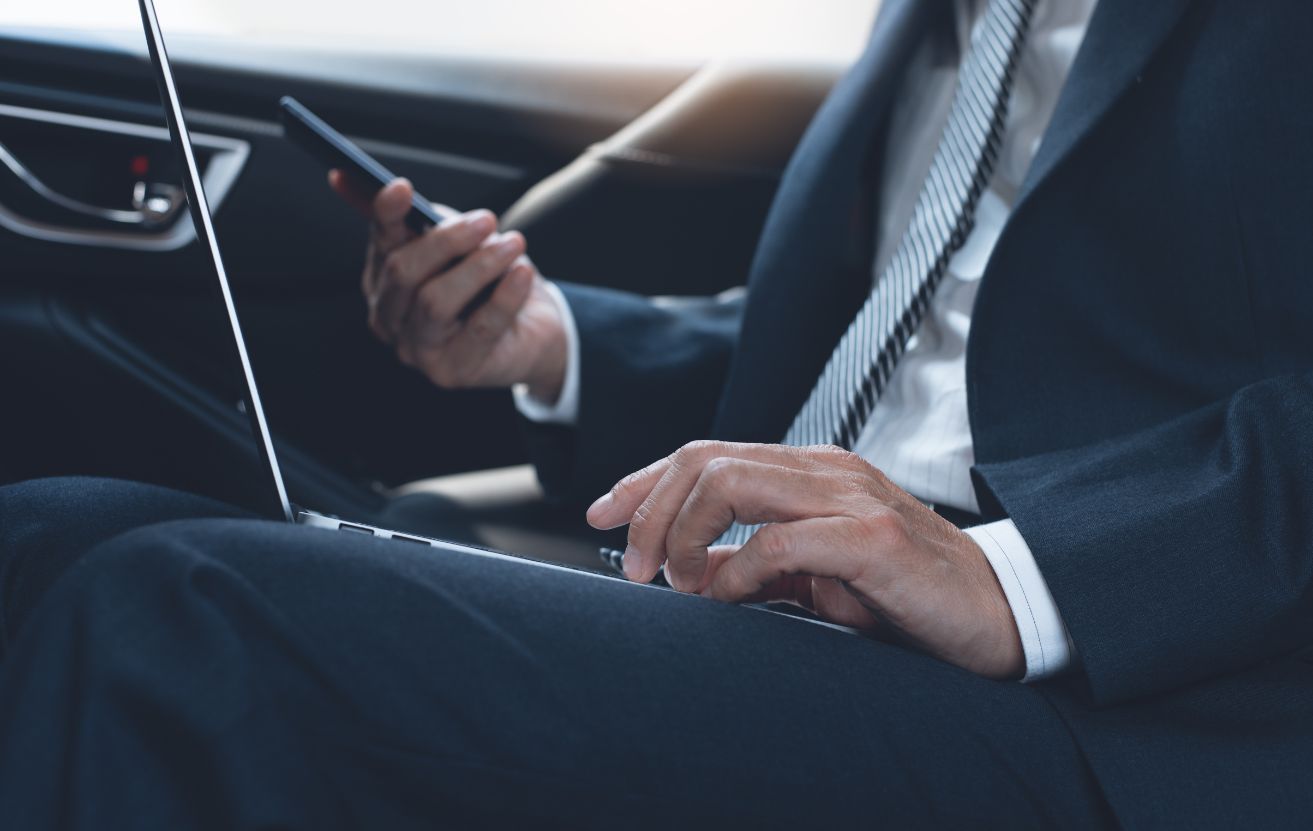 Executive on their laptop in the back of a private car
