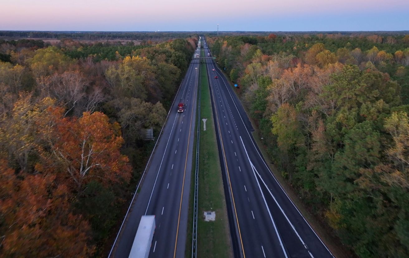View of a highway leading toward a city skyline at dusk during Thanksgiving travel week