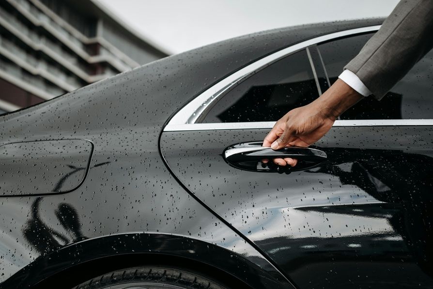 Man opening black car door in rain